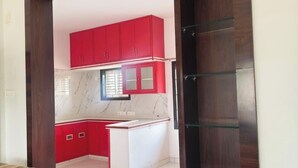 Una cocina con armarios rojos, un salpicadero de mármol y un marco de puerta de madera.