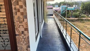 Un pasillo con baldosas estampadas, una barandilla de metal y vistas al exterior.
