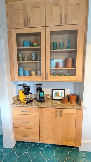 Eine Küche mit Holzausstattung, einer Arbeitsplatte mit Kaffeemaschine und einem gemusterten Boden.