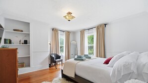 Ein Schlafzimmer mit Bett, Stuhl, Schreibtisch und Bücherregal.