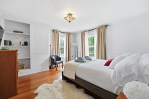 Ein Schlafzimmer mit Bett, Stuhl, Schreibtisch und Bücherregal.