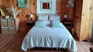 A wooden-paneled room with a bed, two nightstands, a mirror, and wall art. - Les Bambous Vacation Rental, for 2 people, downtown Billom (one pet allowed) (Billom)