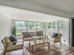 Une pièce spacieuse avec de grandes fenêtres, une table basse en bois et un ensemble de canapés.