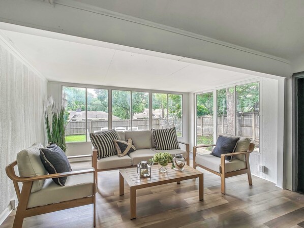 A spacious room with large windows, a wooden coffee table, and a sofa set.