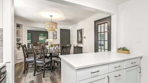 Een moderne keuken met een centraal eiland, houten stoelen en een kroonluchter.