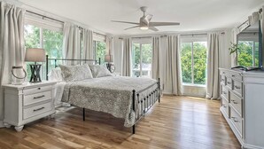 Een slaapkamer met een bed, een dressoir, een nachtkastje en een plafondventilator.