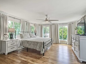 Une chambre à coucher comprenant un lit, une commode, une table de chevet et un ventilateur de plafond.