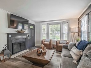 Un salon avec une cheminée, un ensemble de canapés, une table basse et un téléviseur fixé au mur.
