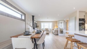 A modern kitchen with a built-in oven and a dining area with a long wooden table and chairs. - Luxury House in Templepatrick I Big Garden I Near Airport & Belfast (Templepatrick)
