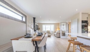 A modern kitchen with a built-in oven and a dining area with a long wooden table and chairs. - Luxury House in Templepatrick I Big Garden I Near Airport & Belfast (Templepatrick)
