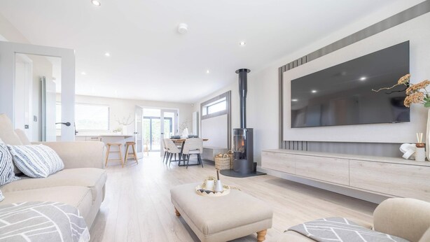 A modern living room with a sofa, ottoman, and a TV mounted on the wall. - Luxury House in Templepatrick I Big Garden I Near Airport & Belfast (Templepatrick)