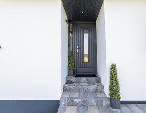 A modern black door with a small window, stone steps, and two potted plants. - Luxury House in Templepatrick I Big Garden I Near Airport & Belfast (Templepatrick)