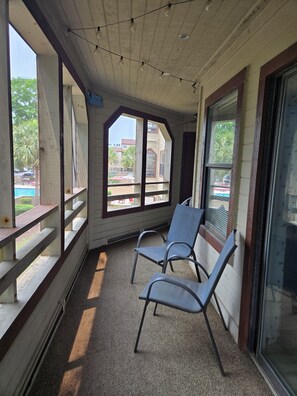 A covered outdoor seating area with chairs, large windows, and string lights. - Ocean Ahh, a beautiful 2 BR/2 BA condo less than .4 miles to the beach (Myrtle Beach)