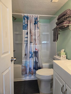 A bathroom with a shower curtain, toilet, and a towel rack. - Ocean Ahh, a beautiful 2 BR/2 BA condo less than .4 miles to the beach (Myrtle Beach)