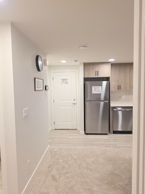A modern kitchen with a stainless steel refrigerator, a dishwasher, and light wood cabinets. - 2-bedroom legal basement unit in Northwest Calgary (Calgary)