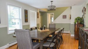 Une salle à manger avec une longue table, des chaises et un lustre.