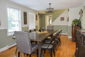 A dining room with a long table, chairs, and a chandelier. - Quiet North Conway home: Hot tub, arcade, outlets! (Conway)
