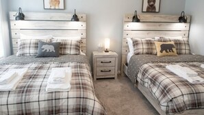 Un lit double avec une couvre-lit à carreaux, deux tables de chevet avec des lampes et une petite table de nuit avec une lampe.