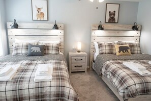 A double bed with a plaid bedspread, two bedside tables with lamps, and a nightstand with a lamp. - Quiet North Conway home: Hot tub, arcade, outlets! (Conway)