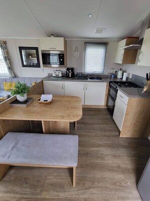 Cocina compacta con microondas, tostadora, pileta, estufa y piso de madera.
