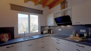 Eine moderne Küche mit weißen Schränken, einem Einbauofen und einem Fenster mit Blick ins Freie.