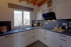 Eine moderne Küche mit weißen Schränken, einem Einbauofen und einem Fenster mit Blick ins Freie.