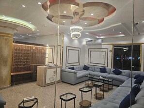 A modern living room with a sectional sofa, a coffee table, and a decorative wall with Arabic script. - Lualuat Rahty (Riyadh)