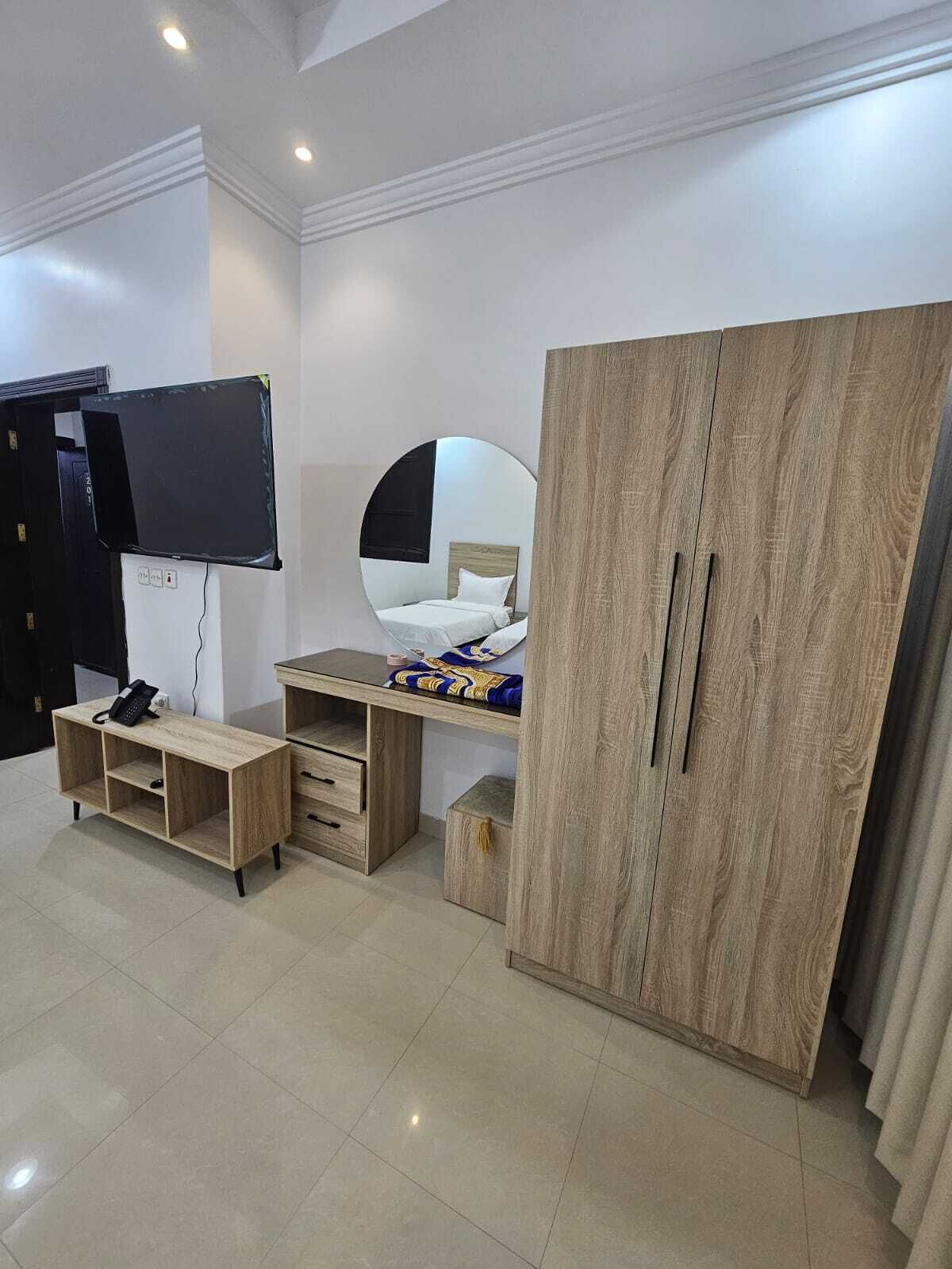 Un dormitorio con cama, televisor, armario y escritorio.