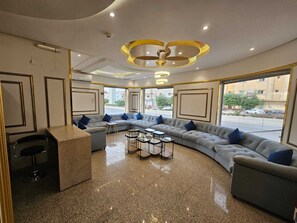 A modern lounge area with a curved sofa, small tables, and a bar counter. - Lualuat Rahty (Riyadh)