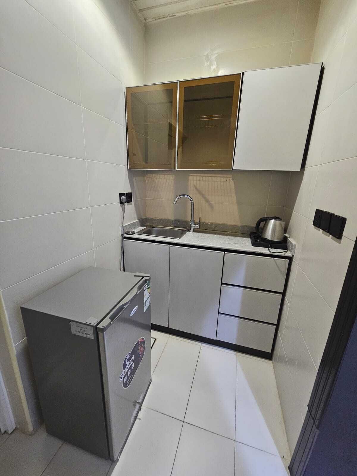 Cocina compacta con refrigerador, lavamanos y estufa.