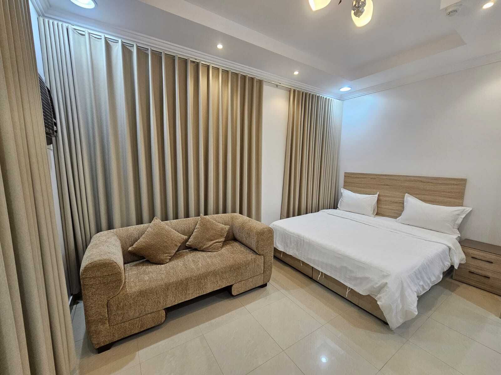Ein Schlafzimmer mit einem Bett, einem Sofa und Vorhängen.