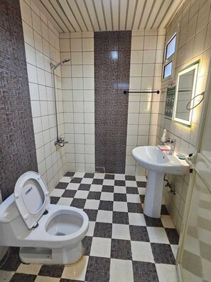 A bathroom with a checkered floor, a toilet, a sink, and a shower. - Lualuat Rahty (Riyadh)