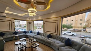 A modern living room with a large L-shaped sectional sofa, a glass coffee table, and a unique ceiling light fixture.
