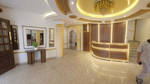 A spacious lobby with a reception desk, a large mirror, and a chandelier.