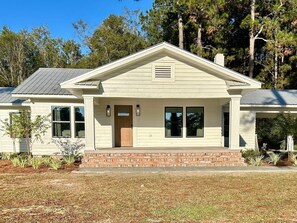 A single-story house with a front porch, a brick entryway, and a small front yard.
