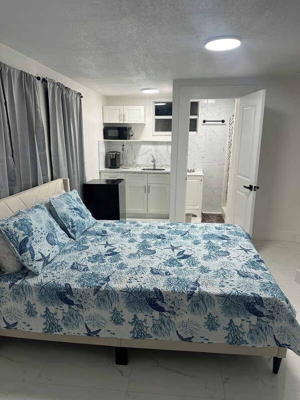 Ein Schlafzimmer mit Bett, einer kleinen Küchenzeile und einem Badezimmer.