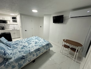 Ein Schlafzimmer mit Bett, Schreibtisch, Stuhl, Fernseher und Kleiderschrank.