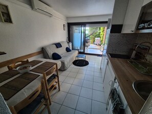 A compact living space with a sofa, dining table, and kitchenette. - Garden level in residence pierre et vacances (Cannes)