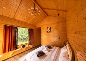 A wooden cabin room with a bed, a window with curtains, a chandelier, and a painting on the wall. - Semporna Fairy Waterfront Resort (Semporna)