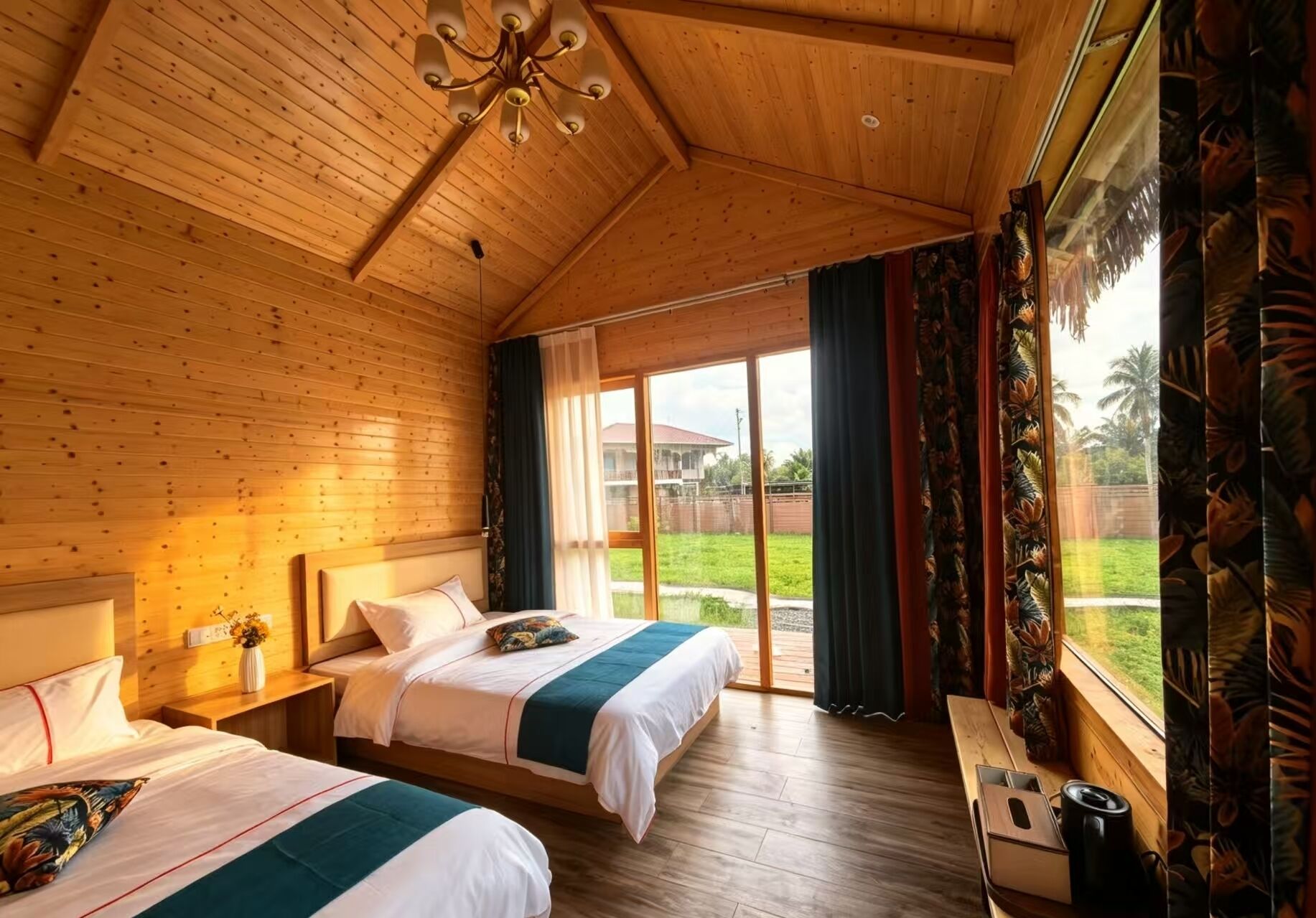 A wooden room with two beds, a chandelier, and a view of a house and garden.