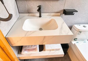 A bathroom with a white sink, black faucet, and a toilet with a green sticker. - Semporna Fairy Waterfront Resort (Semporna)