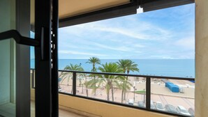 Un balcón con vista a la playa, palmeras y el mar.