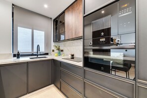 A modern kitchen with a built-in oven, a sink, and a dining area visible through a glass partition. - LXR Matisse 2-Bedroom, Beachfront (Fuengirola)