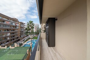 Ein Balkon mit Blick auf ein Schwimmbad und angrenzende Gebäude.