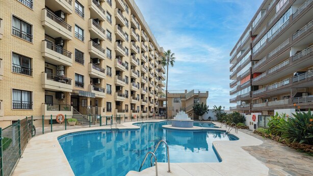 Un edificio residencial de varios pisos con piscina y puesto de socorrista.