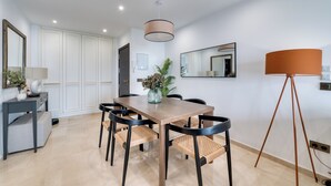 Un comedor moderno con una mesa de madera, sillas negras, un jarrón con flores y una lámpara de pie.