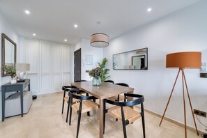 A modern dining area with a wooden table, black chairs, a vase with flowers, and a floor lamp. - LXR Matisse 2-Bedroom, Beachfront (Fuengirola)