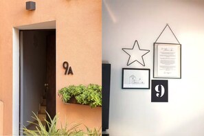 Ein Gebäudeeingang mit einer Nummernschild, einer Sterndeko und gerahmten Dokumenten an der Wand.