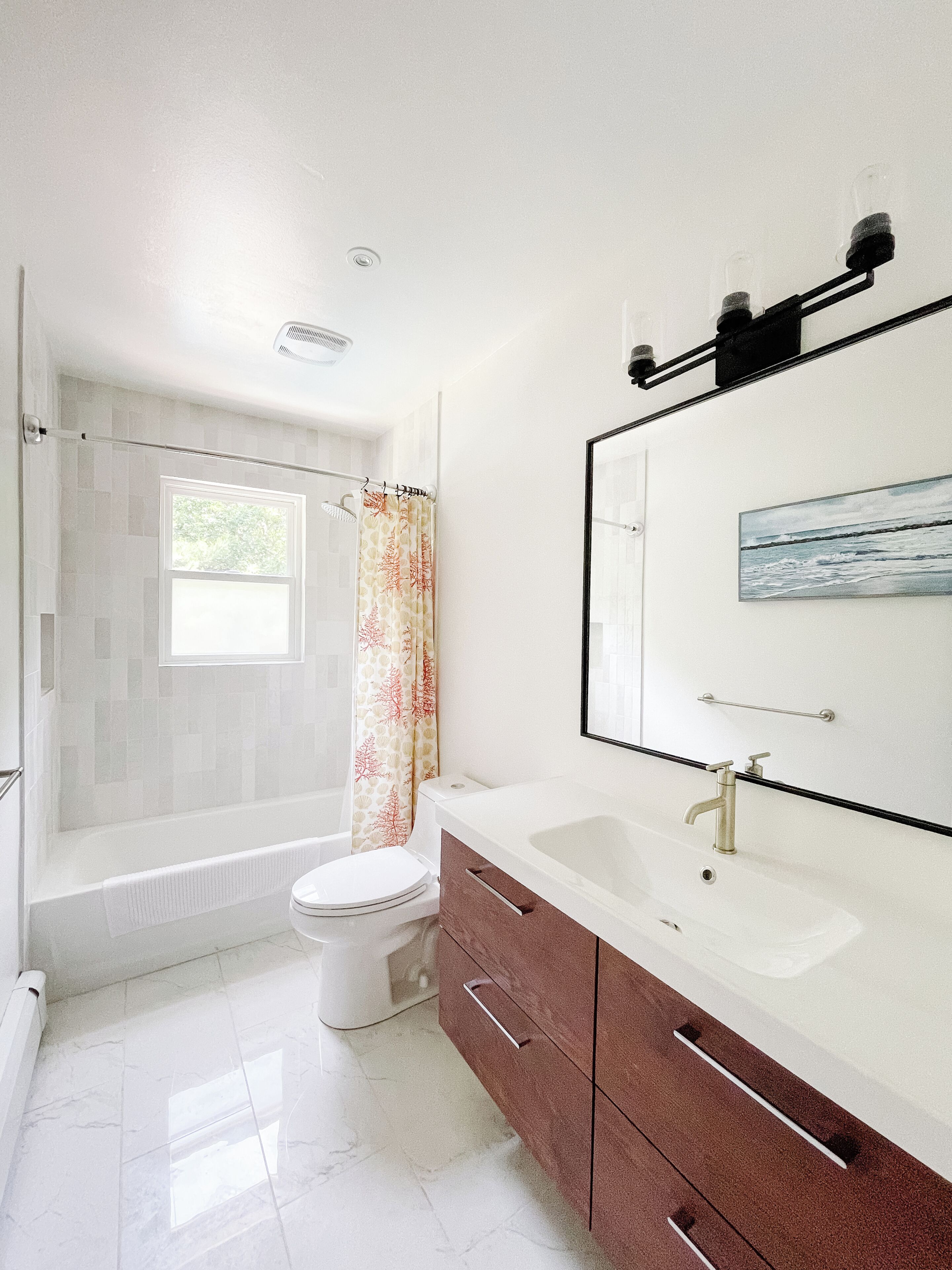 A modern bathroom with a bathtub, toilet, vanity, and a large mirror.