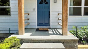 A house with a blue door, a porch with steps, and a small garden.